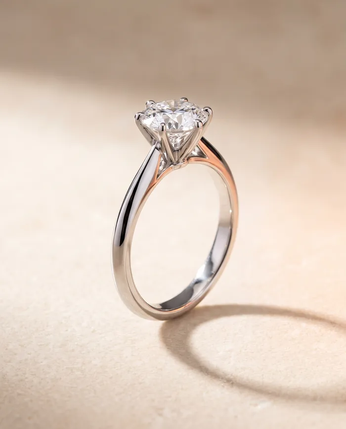 A platinum solitaire ring holding a 1.80 carat round brilliant diamond in six claw prongs above a fine tapering band
