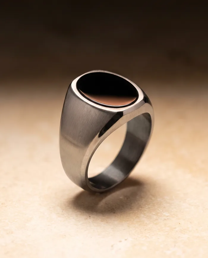 A brushed grade 5 titanium signet ring with a hand-cut black onyx cabochon set into its oval face