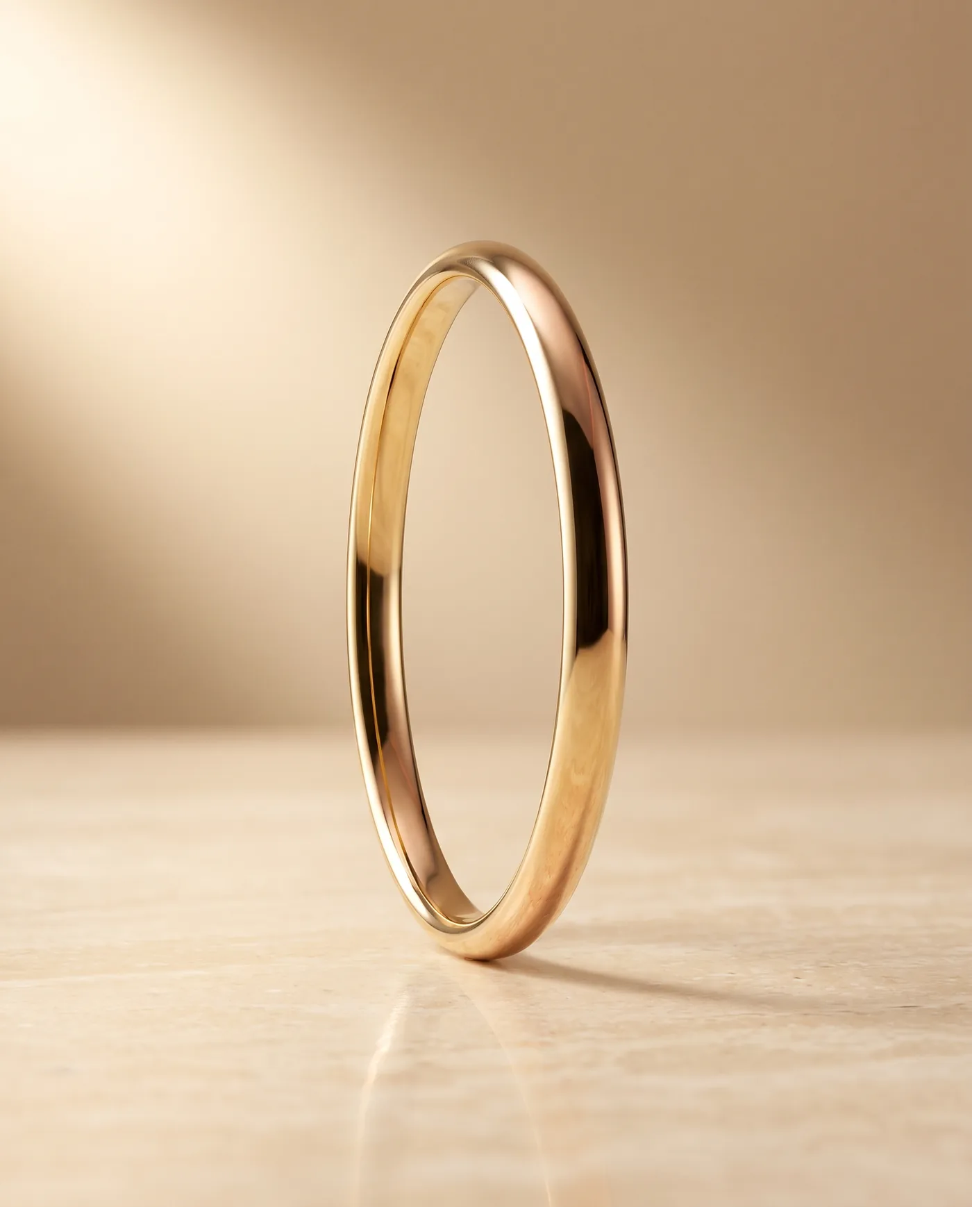 A polished 18k yellow gold bangle, a smooth seamless tube with a mirror finish