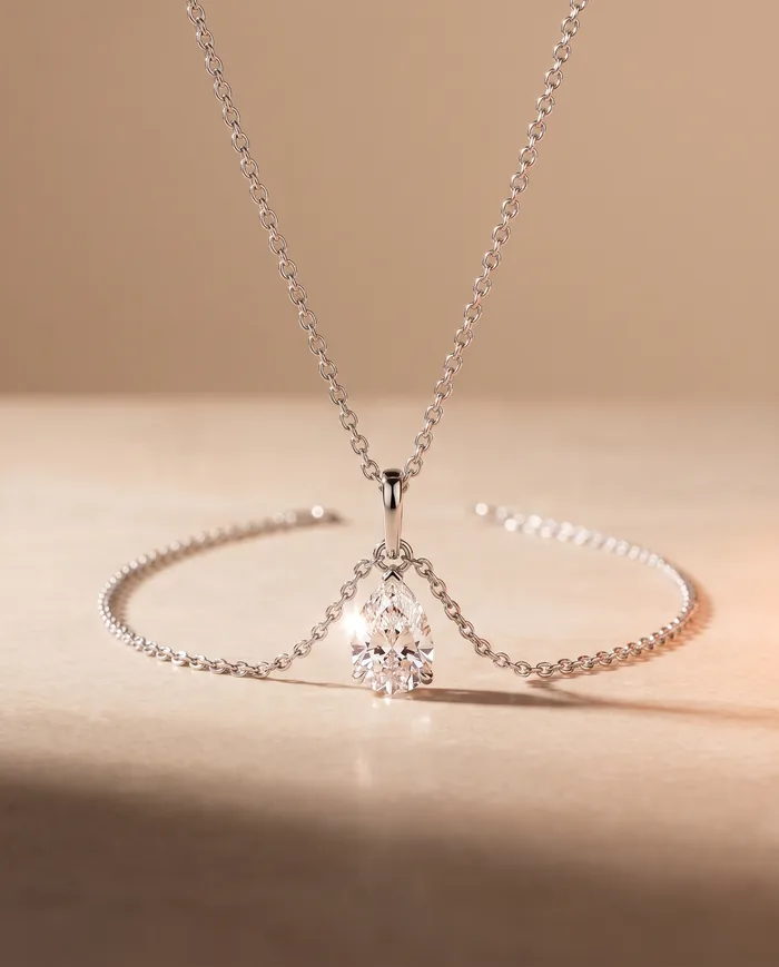 A fine 18k white gold chain suspending a 3.40 carat pear-cut diamond from a slim hinged bail