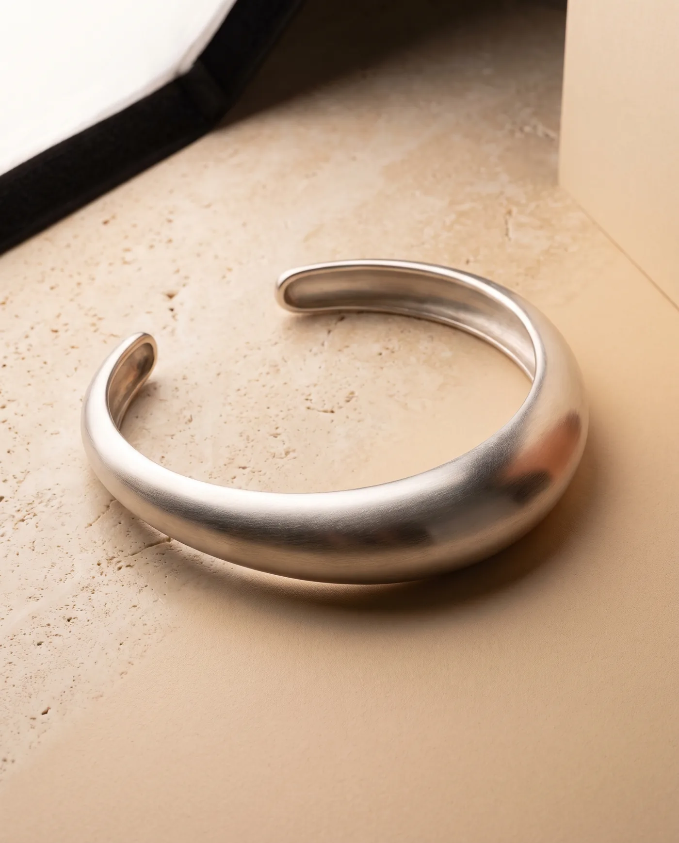 A sculptural sterling silver torque collar tapering to two rounded open ends, in matte-brushed silver