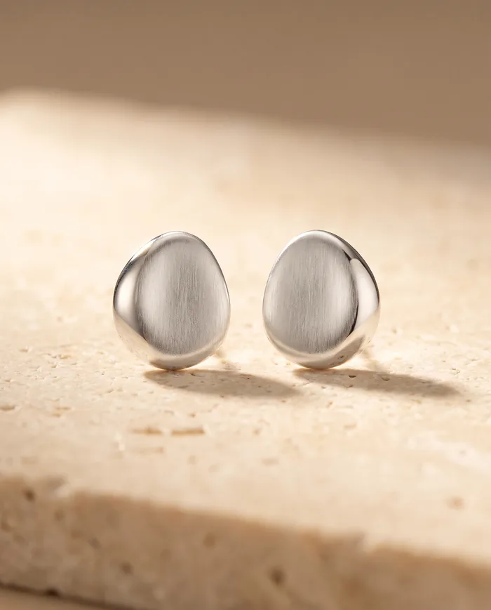 A pair of sculptural sterling silver stud earrings, smooth asymmetric pebble forms in brushed silver